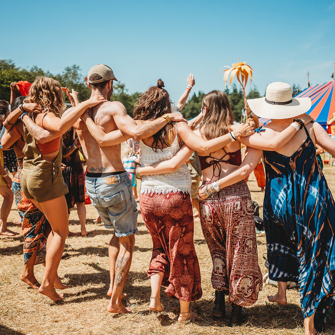 Group of people in a field dancing with linked arms